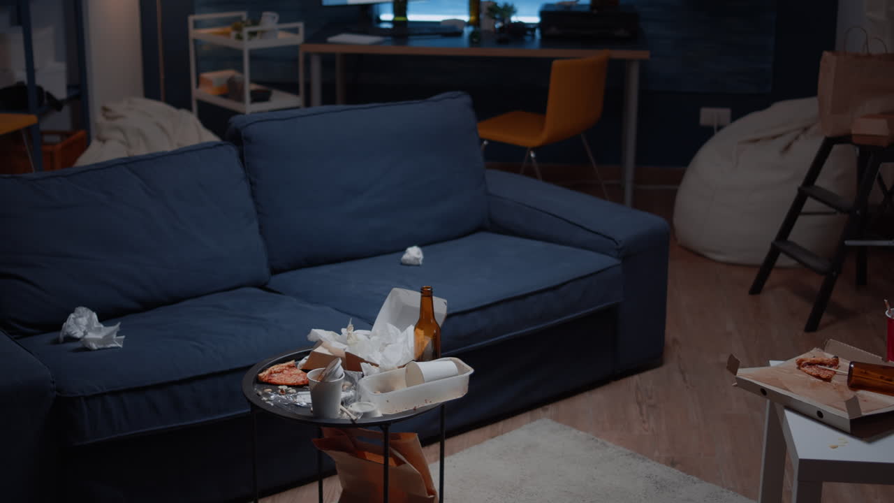 Leftover of pizza empty beer bottles and napkins on table in messy living room
