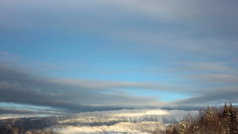 nubes rodando sobre el paisaje montañoso nevado en invierno al amanecer