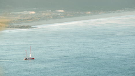 rippling water with ship sailing during hazy morning at the beach of nazare, portugal