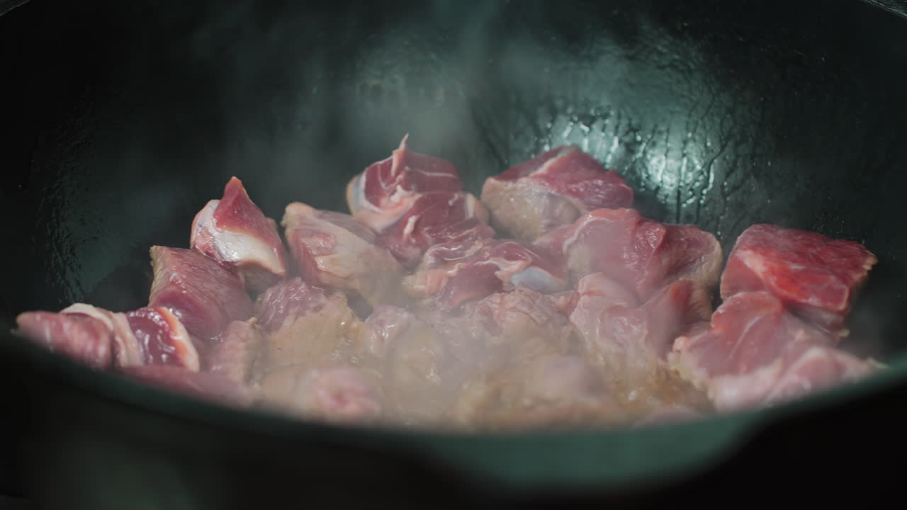 Potongan Daging Mentah Sedang Digoreng dan Mengeluarkan Uap di Panci Panas