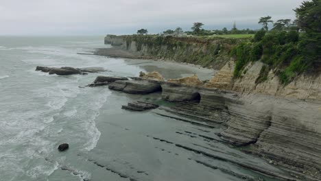 vista aérea inversa destino turístico popular de los acantilados de omau con un paisaje costero áspero y crudo único en el cabo de viento en la isla sur, nueva zelanda aotearoa