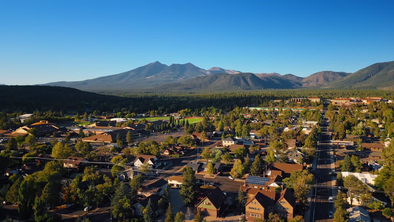 Flying over the green cityscape of Flagstaff, Arizona, USA. Beautiful lush woods and mountains at backdrop