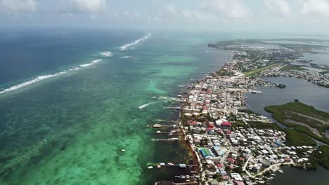 Aerial-view-of-the-city-of-San-Pedro,-Belize-and-the-clear-ocean,-drone-tilt-forward