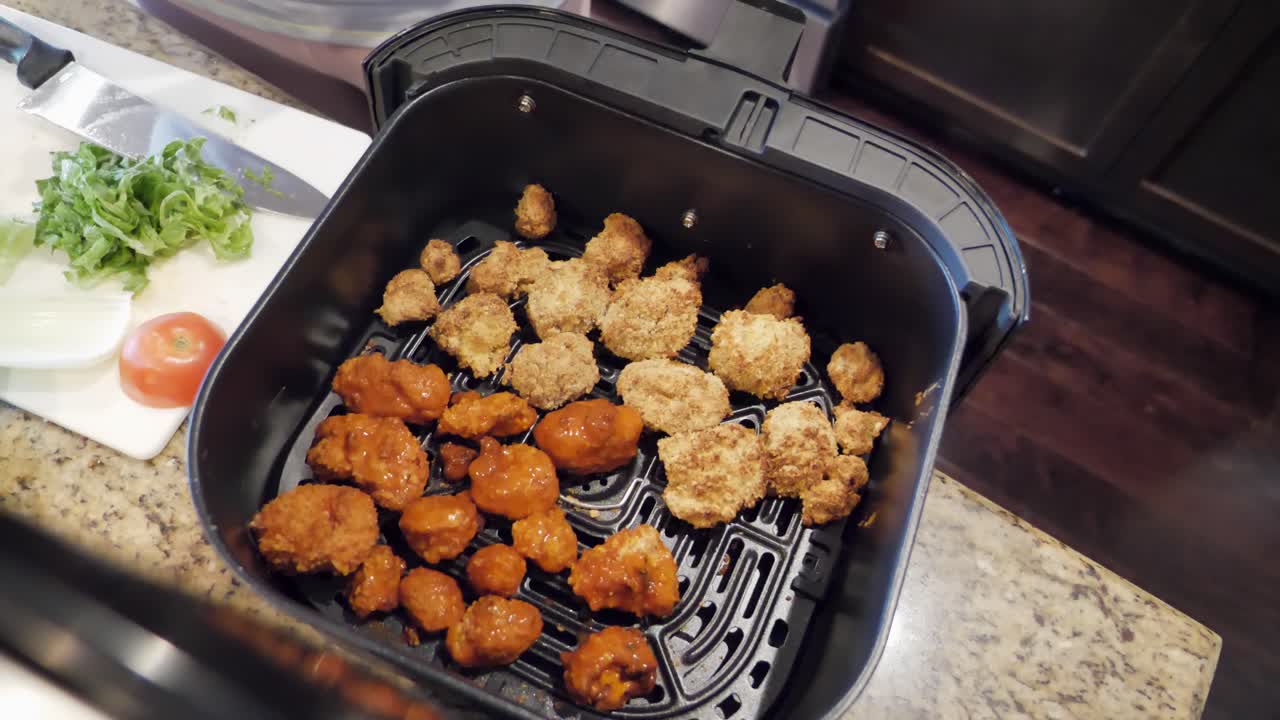 Home cooking cauliflower buffalo bites in air fryer, pet dog looks longingly at food, vegetarian