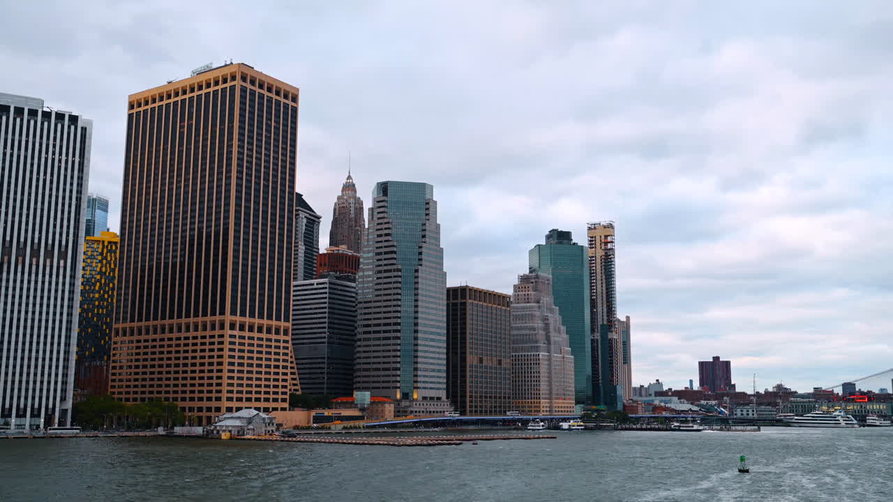 Nova Iorque, EUA, 5 de maio de 2025: Arranha-céus do Distrito Financeiro ao longo da orla do East River. Vista dos edifícios de escritórios e píeres do centro de Manhattan sob um céu nublado, a partir do rio.