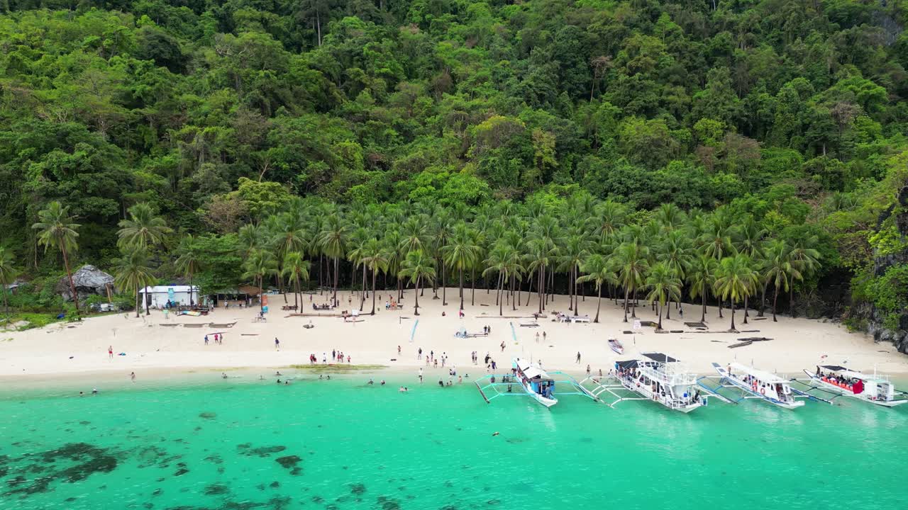 Turisti arrivano su canoe a bilanciere e si rilassano sulla spiaggia sabbiosa di El Nido, Palawan