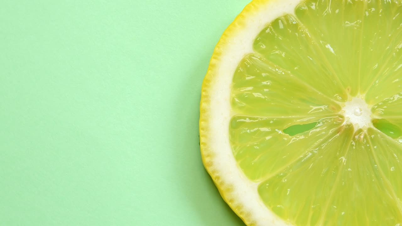 una rebanada de limón girando de cerca sobre un fondo verde