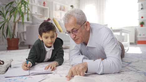 Reifer-Vater-Liegt-Zu-Hause-Auf-Dem-Boden-Und-Hilft-Seinem-Sohn-Beim-Lernen.