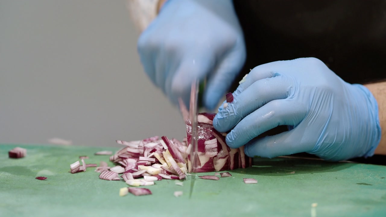 Chef in Blue Gloves Dicing Red Onion on Cutting Board