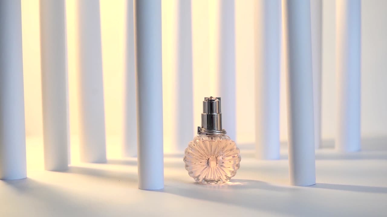 Flacone di profumo in vetro su sfondo bianco con colonne e luci