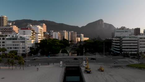 movimiento aéreo ascendente que revela el canal que conecta el lago de la ciudad con la playa y el océano de leblon en primer plano y río de janeiro con la montaña corcovado en el fondo al amanecer