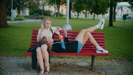 two women relaxing on a park bench