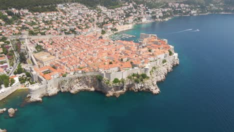 fotografía rotativa aérea de la vieja ciudad de dubrovnik, croacia, con acantilados rocosos a lo largo de la costa y las murallas de la fortaleza visibles desde arriba en un día soleado