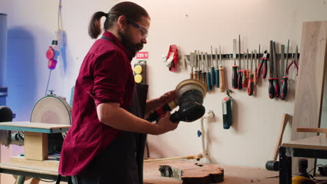 hombre con gafas de protección utiliza equipo de lijado orbital después de consultar esquemas