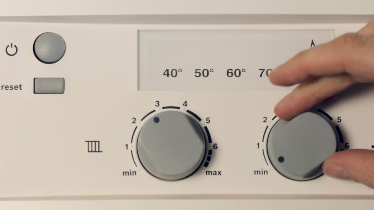 Male fingers adjust the control panel of the gas boiler for hot water and heating in the apartment. Buttons and digital display. Home heating concept