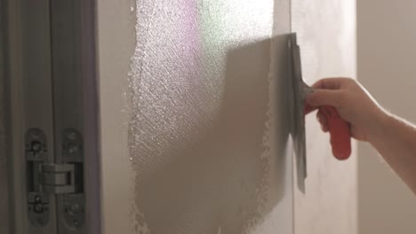 worker applies decorative plaster with a thin spatula. giving a unique texture t