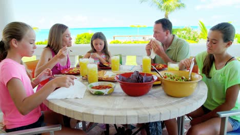 young caucasian family eating lunch outdoors by beach