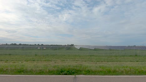 a drive down a country road reveals a solar farm surrounded by fields of crops as well as an oil tank at the end of the clip