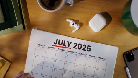 person planning for july 2025 on a desk calendar