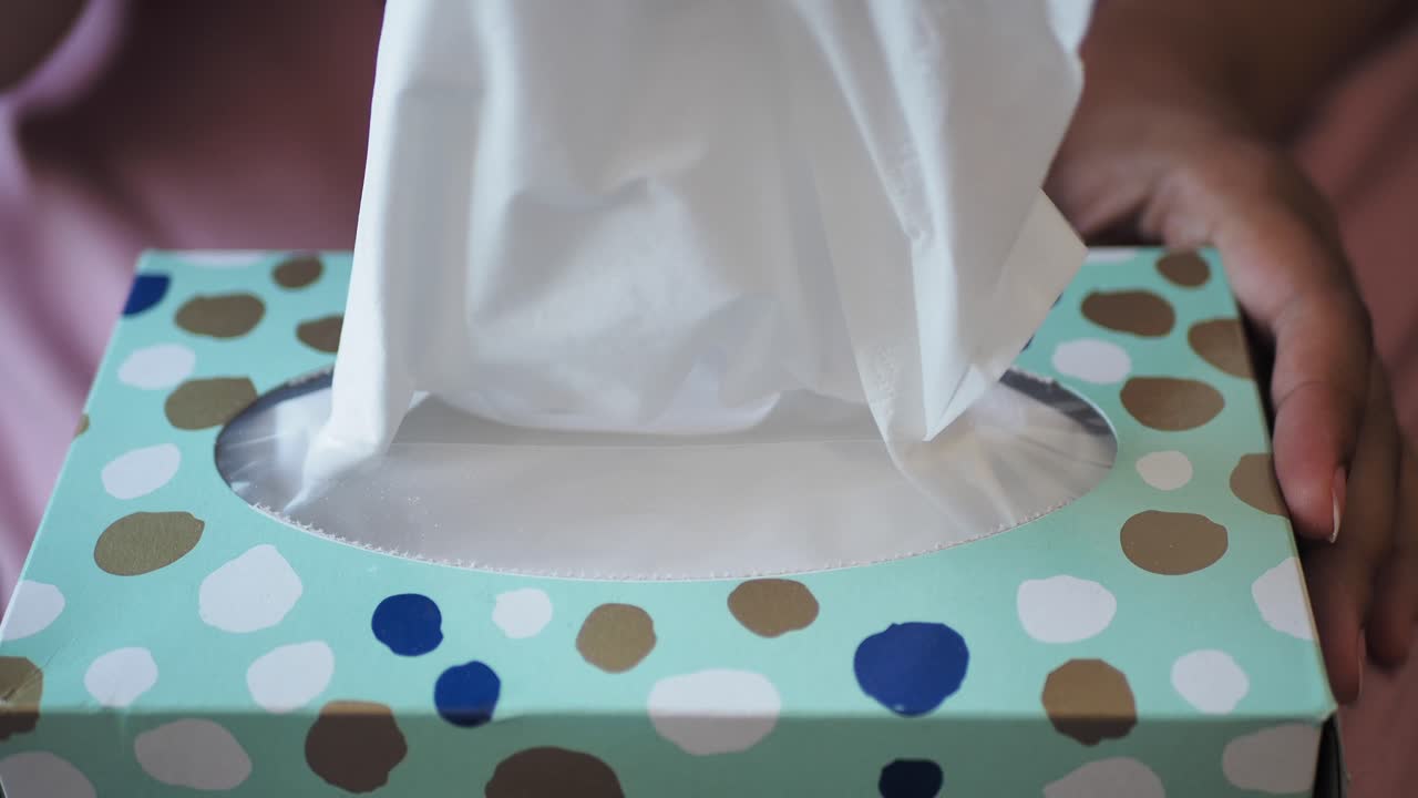 mujer tomando tejidos de una caja de tejidos