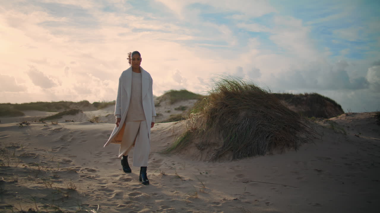 una chica viajera va a las dunas de la playa en un viaje de fin de semana. una mujer serena admira la naturaleza salvaje.