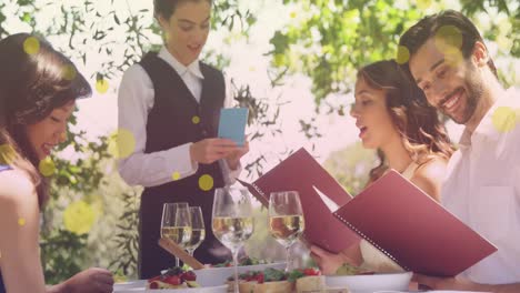 animación de puntos amarillos sobre felices amigas y amigos caucásicos ordenando en un restaurante
