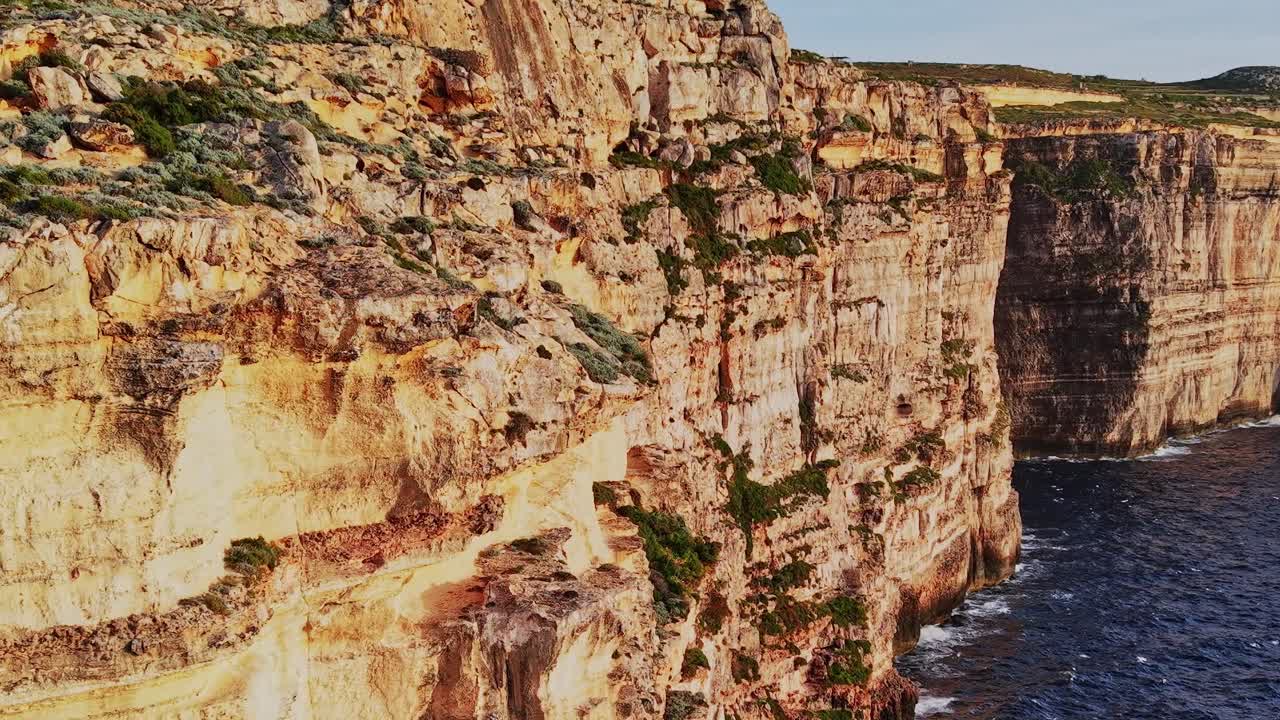 Cliffs along the coast of Malta with ocean waves crashing below
