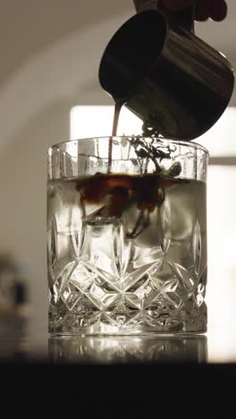 vertical view of pouring black espresso coffee into gin and tonic, czechia