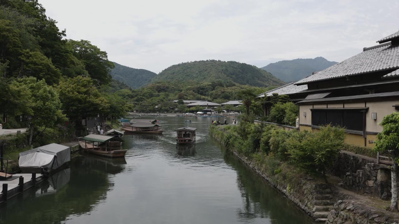 Řeka Kacura v Kjótu, Japonsko. Lodě, budovy a krajina.
