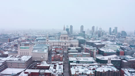 dolly back aerial drone shot of st pauls cathedral snowing city of london
