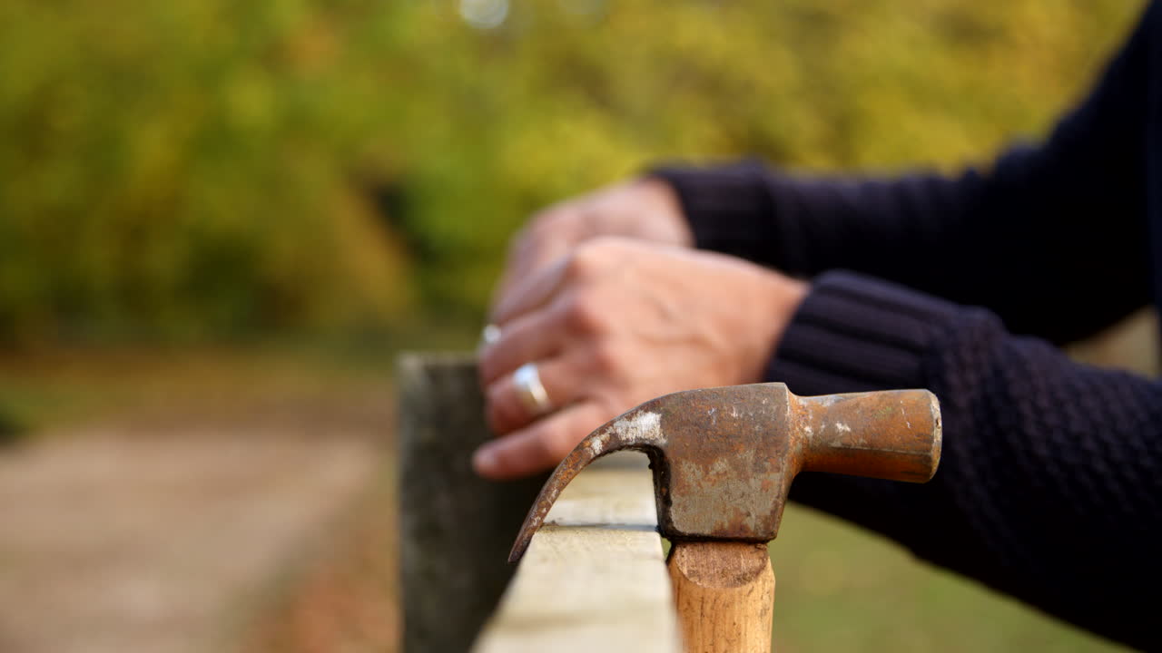 Close Up Of Man Measuring Fence Prior To Repair