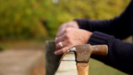 Close-Up-Of-Man-Measuring-Fence-Prior-To-Repair