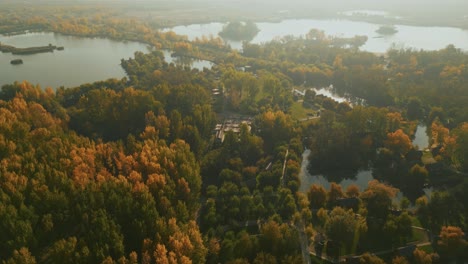 lakes and autumn trees in mist in doaga, romania on sunny morning. aerial orbiting shot