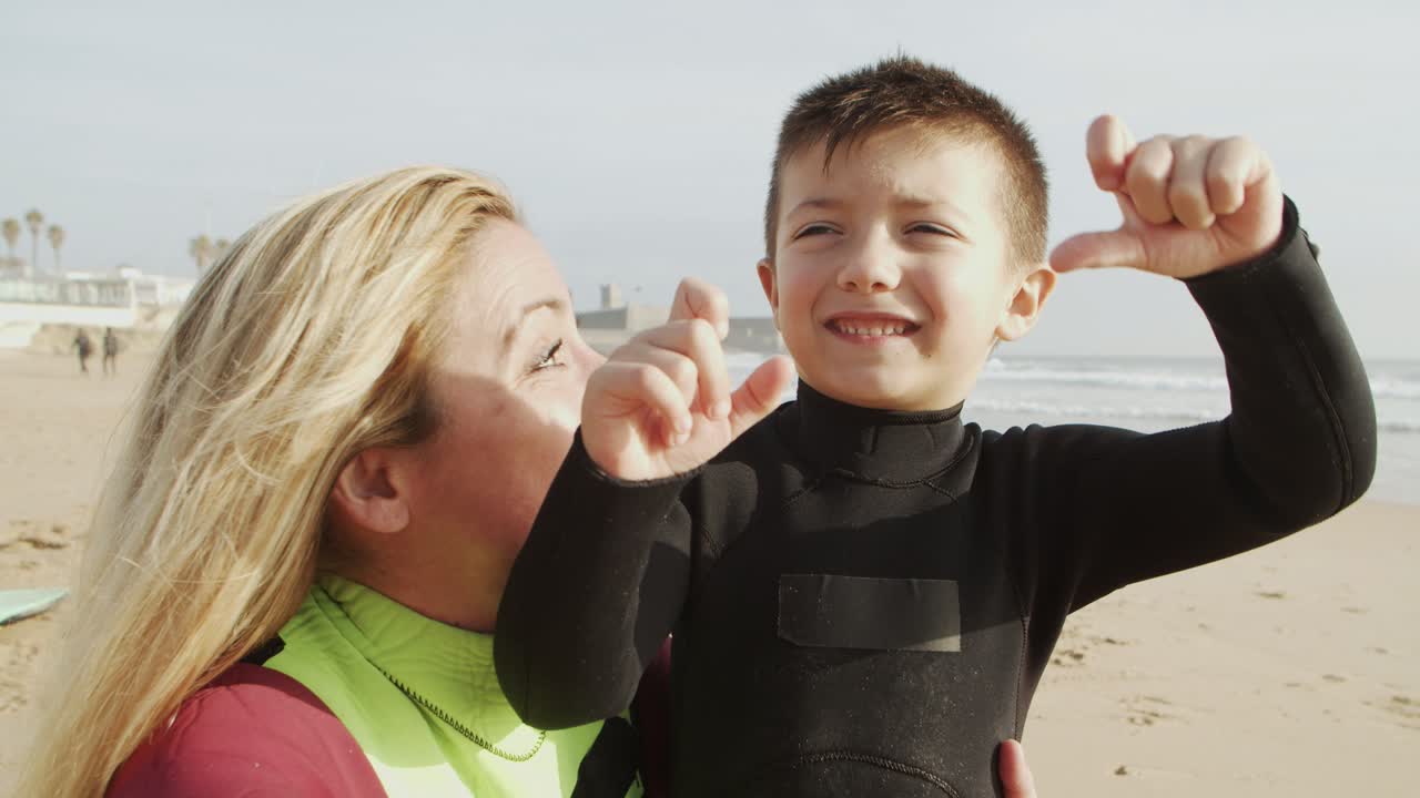Mother and son in wetsuits smiling at camera