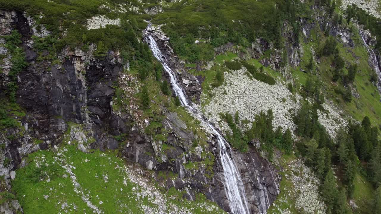 enorme cascada rodeada de mucha grava y unos pocos árboles que conducen por un acantilado en los alpes en kaernten, austria