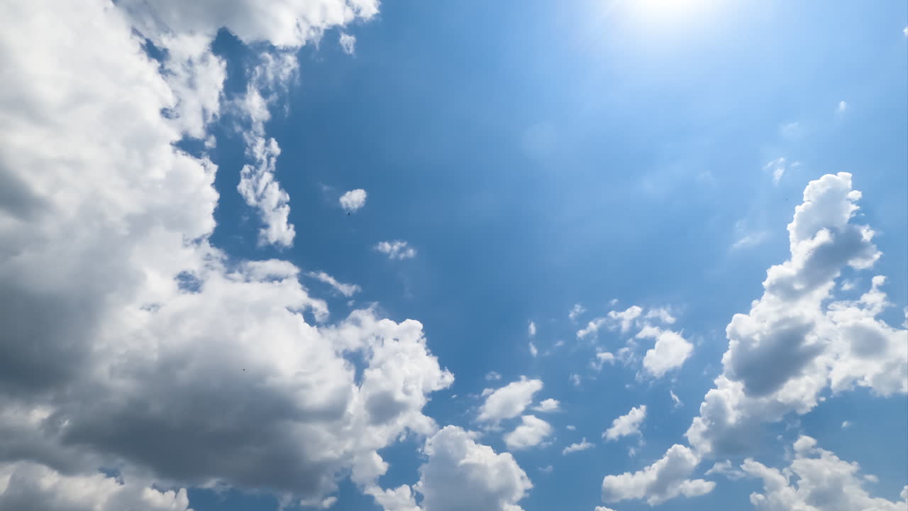 Lovely fluffy clouds in the rays of bright sky. Shape-changing cloudscape on beautiful sunny day from low angle view. Timelapse.