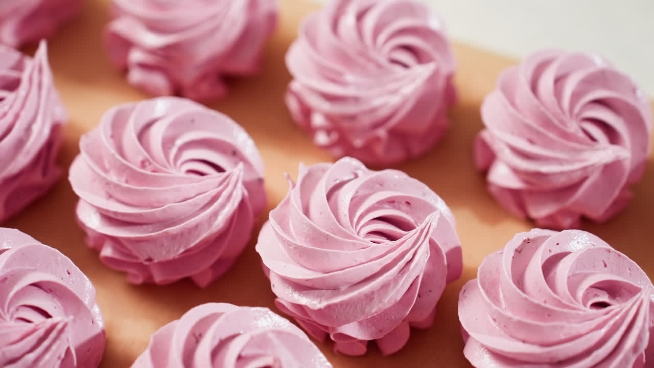 Close up of creamy swirl pink cupcakes neatly arranged on brown baking paper, showcasing smooth texture, elegant piping, and vibrant pastel color