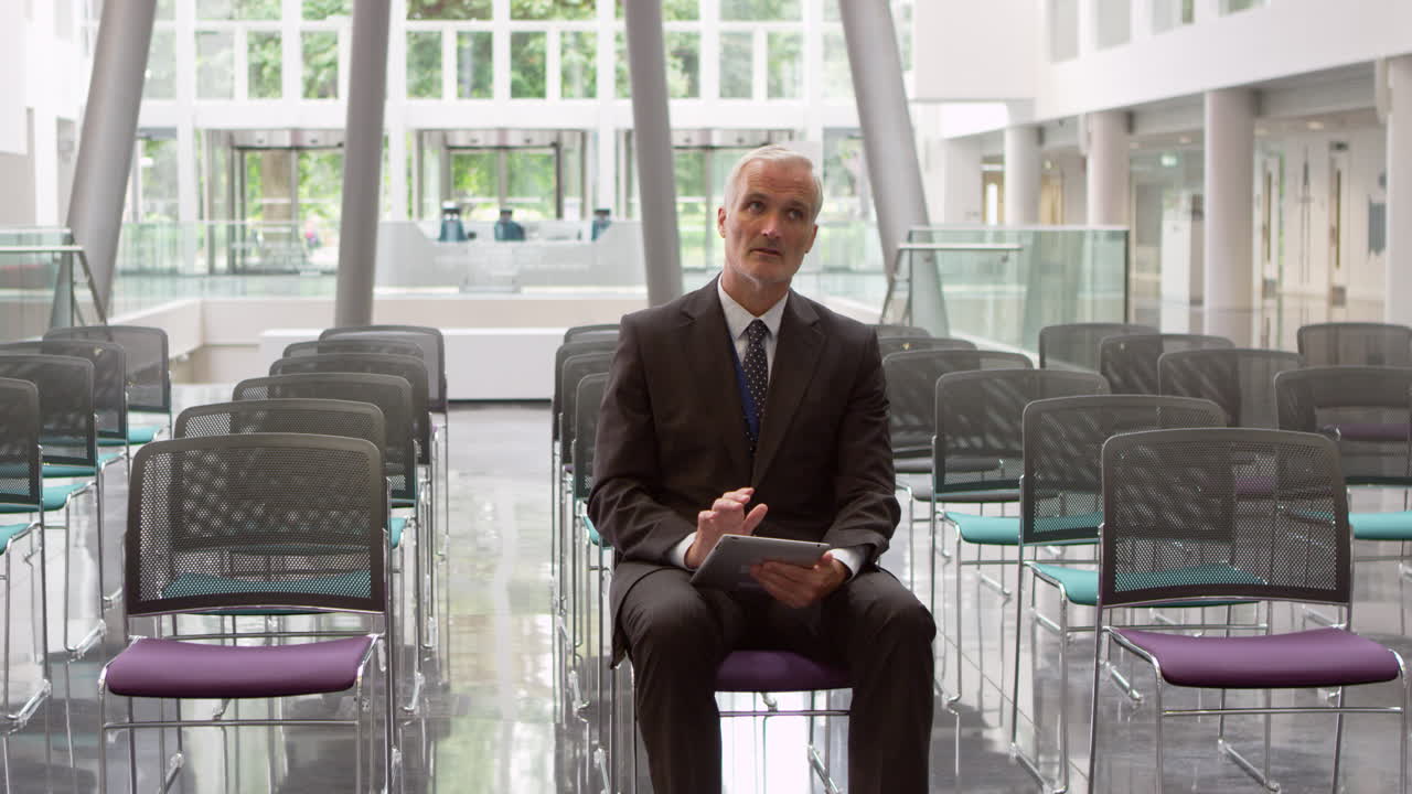 un hombre de negocios en un auditorio vacío prepara un discurso filmado en r3d.