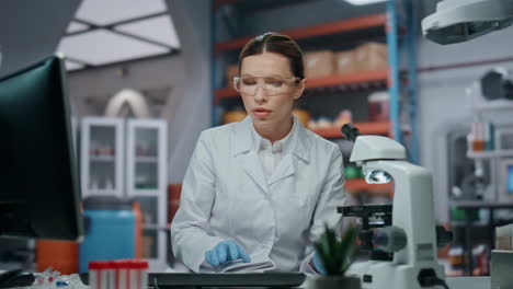 médico ocupado trabajando en el laboratorio escribiendo en la computadora con gafas de protección de cerca.