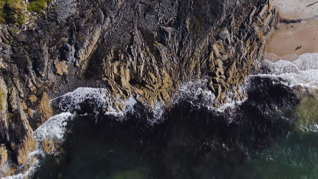 Vista a volo d'uccello 4K di onde costiere che si infrangono sulle rocce, al rallentatore.