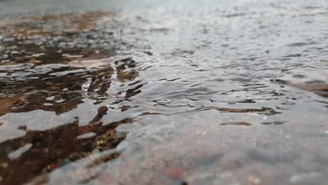 Gotas-De-Agua-Cayendo-En-Un-Charco-De-Agua-En-Movimiento-Rápido-Sobre-Ladrillos-De-Arenisca,-Imágenes-En-Cámara-Lenta