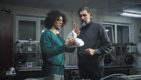 two men examining a 3d-printed object in a workshop