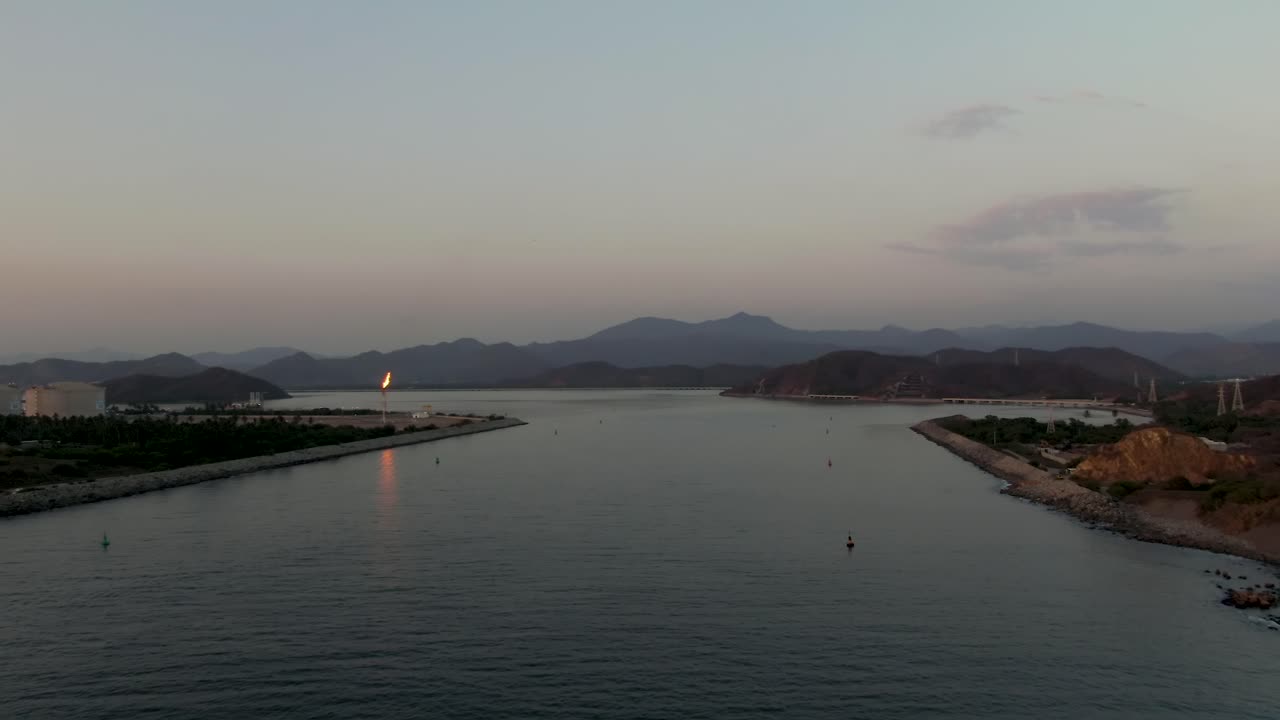 Slow aerial dolly over El Edén breakwater and Laguna de Cuyutlán at sunset in Manzanillo, Colima, Mexico