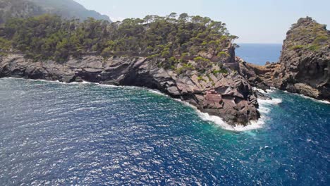 Flying-arround-a-rough-cliff-bay-at-mallorca-with-mountain´s-and-yacht´s-in-the-backround