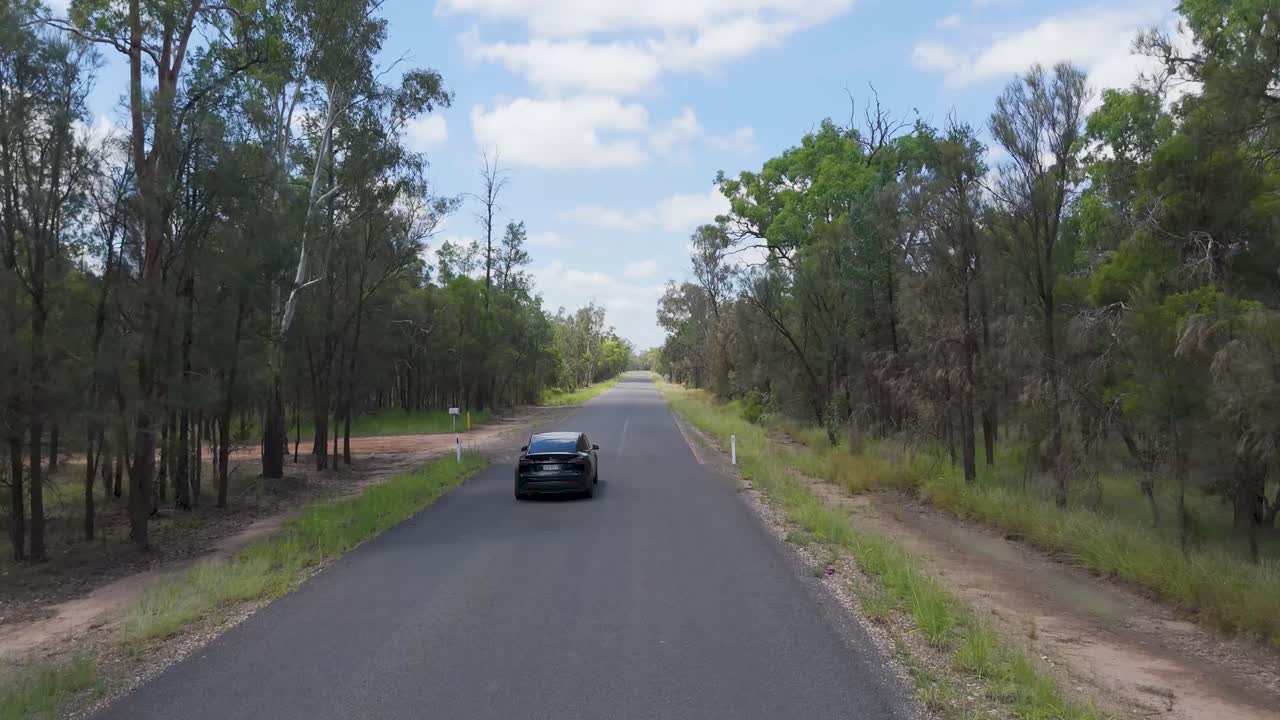 coche eléctrico conduciendo a través de la exuberante carretera del bosque australiano