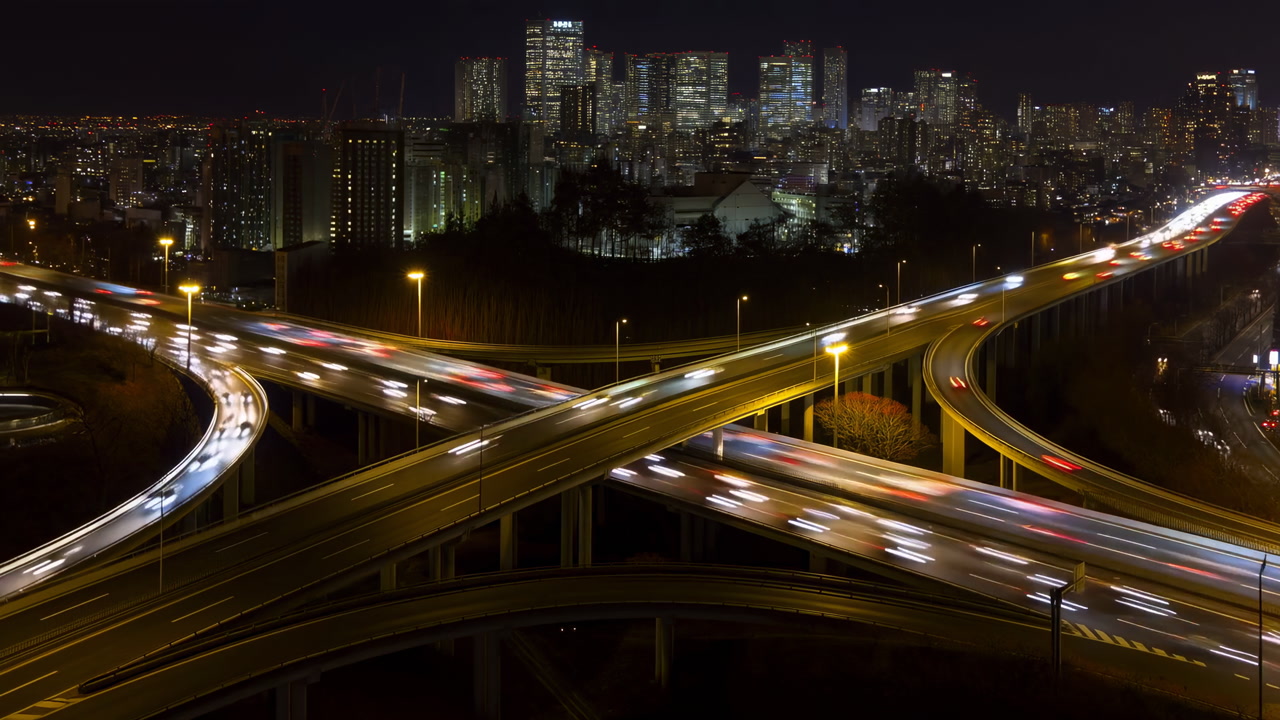 Nighttime City Interchange With Light Trails Sweeping Aerial View Of Multilayered Overpass And Flowing