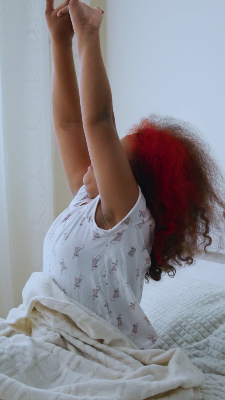 Giovane donna che si sveglia e si stira a letto al mattino