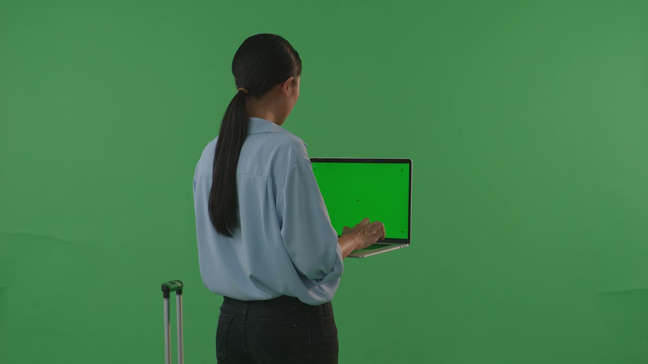 mujer trabajando en una computadora portátil con una maleta