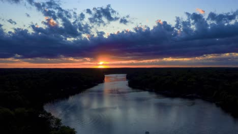 Luftaufnahme-Eines-Dramatischen-Sonnenuntergangs-über-Dem-See-Mit-Fließenden-Wolken