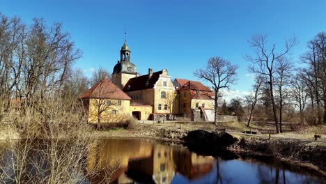 Schloss-Lielstraupe-An-Einem-Sonnigen-Frühlingstag,-Luftaufnahme-über-Dem-Teich